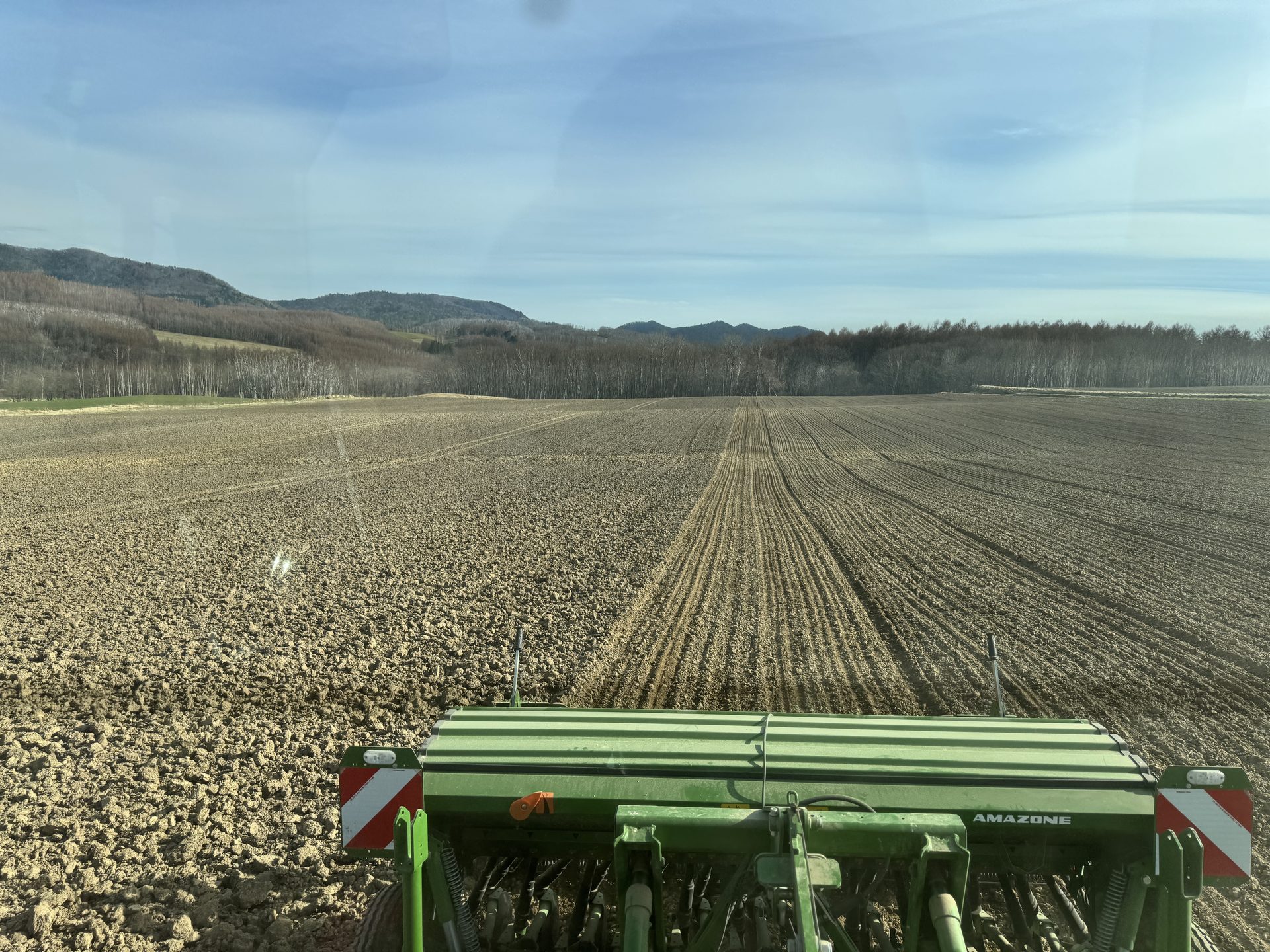 播種後のオホーツクの広大なほ場。AMAZONEの播種機越しに見える景色